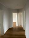 Flur mit weißen Wänden und einem Design-Vinyboden in Holzoptik mit Zugang zu weiteren Zimmern. - Schöne 4-Zimmer-Wohnung mit Balkon zu vermieten!