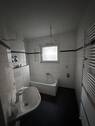 Tageslichtbad mit weißen Wandfliesen, grauen Bodenfliesen und weißer Badewanne, Waschbecken und WC. - 4 Zimmer Etagenwohnung zur Miete in Bad Homburg vor der Höhe