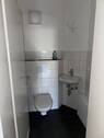 Gäste WC mit weißen Wand- und grauen Bodenfliesen, mit weißem Hänge WC und Waschbecken. - 4 Zimmer Etagenwohnung in Bad Homburg vor der Höhe