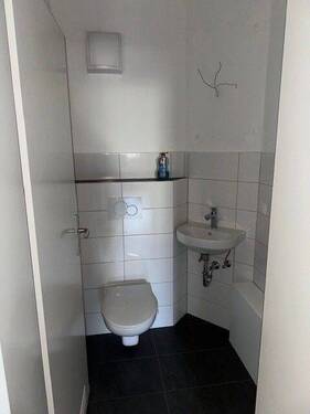 Gäste WC mit weißen Wand- und grauen Bodenfliesen, mit weißem Hänge WC und Waschbecken. - 4 Zimmer Etagenwohnung in Bad Homburg vor der Höhe