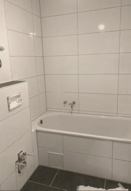 Bad mit weißen Wandfliesen und dunklem Boden mit Badewanne - Baustelle.PNG - 2 Zimmer Etagenwohnung in Flörsheim