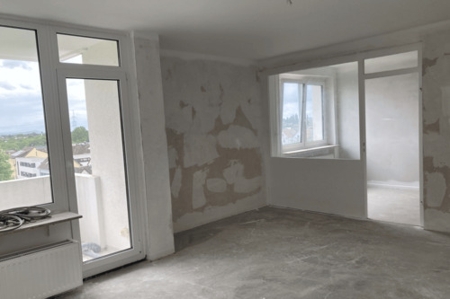 Wohnzimmer mit Zugang zum Balkon und Blick in die Wohnküche mit Glastrennwand - 