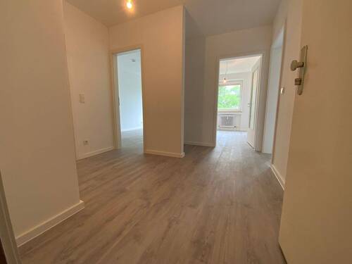 Blick von Wohnungseingangstür in Diele mit grauem PVC-Boden und weißen Wänden von dort sieht man die Zimmereingänge mit weißen Türrahmen - 2 Zimmer Etagenwohnung zur Miete in Meerbusch