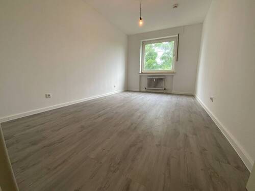 Blick in Schlafzimmer mit grauem PVC-Boden und weißen Wänden mit einem weißen Fenster - 