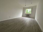 Blick in Schlafzimmer mit grauem PVC-Boden und weißen Wänden mit einem weißen Fenster - 