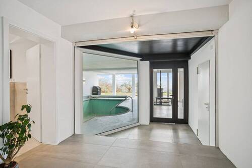 Weitläufiger Flurbereich im UG mit stilvollem Blick auf Pool und Garten - 