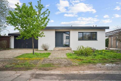 Moderne Vorderansicht eines Einfamilienhauses mit Doppelgarage und zusätzlichen Stellplätzen - 