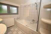 Badezimmer mit Dusche, Wanne und Fenster - 