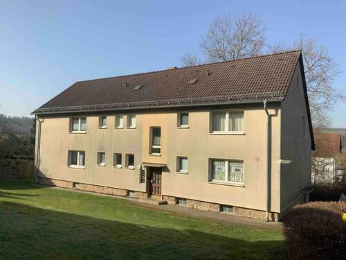 Blick auf das zweistöckige Mehrfamilienhaus mit Rasenfläche vor der Haustür - Etagenwohnung mit 46,30 m² in Melsungen zur Miete