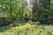 Gartenparadies umgeben von Bäumen, Sträuchern und Blumen - 