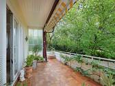 Großer, überdachter Balkon mit idyllischem Blick auf alten Baumbestand - 