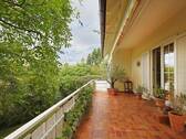 Großer, überdachter Balkon mit idyllischem Blick auf alten Baumbestand - 