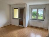Wohnzimmer mit Zugang zum Balkon und hochwertigem PVC-Belag in Holzoptik - 2 Zimmer Etagenwohnung zur Miete in Bad Vilbel