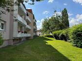 Rückansicht des mehrstöckigen Wohngebäudes mit Balkonen, umgeben von Grünanlagen mit Bäumen und grünen Sträuchern - Etagenwohnung mit 64,60 m&sup2; in Bad Vilbel zur Miete