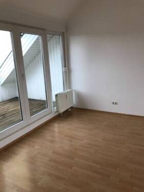 Wohnzimmer mit Dachschrägen, Bodenbelag in Holzoptik und Zugang zur Dachterrasse - 
