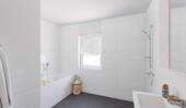 Ein modern gefliestes Bad inklusive Badewanne - 