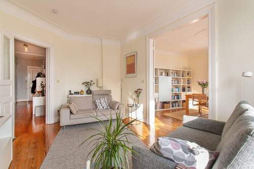 Einladendes Wohnzimmer mit gepflegtem Dielenboden und Stuckdetails - 3 Zimmer Etagenwohnung zum Kaufen in Hamburg