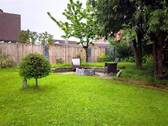Blick in den Garten auf den Sitzbereich mit Feuerstelle - 