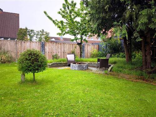 Blick in den Garten auf den Sitzbereich mit Feuerstelle - 