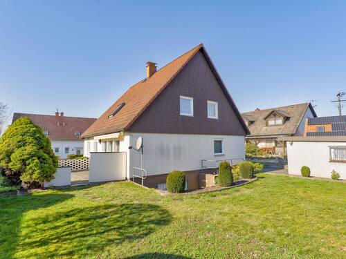 Rückansicht des Einfamilienhauses mit großzügiger Rasenfläche und gepflegtem Gartenbereich - 