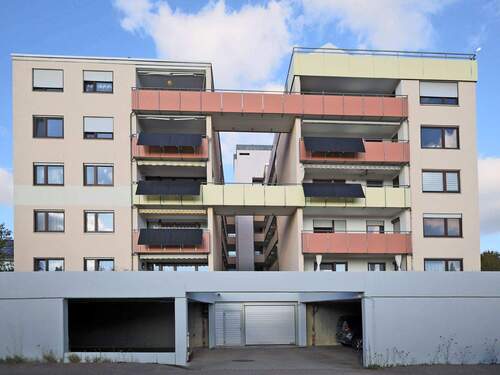 Hausansicht mit Tiefgarageneinfahrt und überdachten Stellplätzen - 