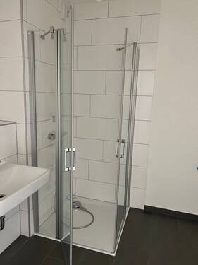Beispiel eines Badezimmers mit Dusche, weißem Wandwaschbecken und Glas-Duschabtrennung mit weißen Wandfliesen auf anthrazitfarbenen Fliesenboden - Etagenwohnung mit 105,50 m&sup2; in Frankfurt am Main zur Miete