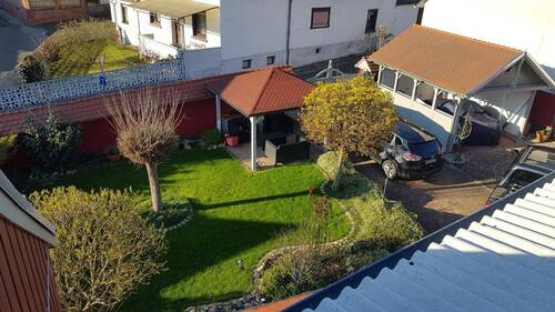 Blick auf Grünfläche, Freisitz und Carport - 