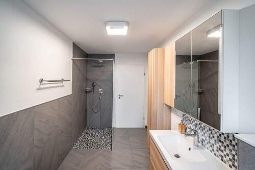 Der Raum ist mit einer Wanne und einer bodengleichen Glasdusche ausgestattet. - 