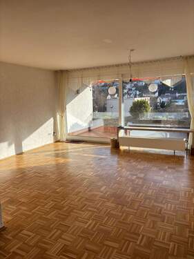 Wohnbereich mit Zugang zum Balkon - Lichtdurchflutete 3-Zimmer-Wohnung in oberster Etage mit großer Balkon-Terrasse, Aufzug & Fernblick in Marktheidenfeld