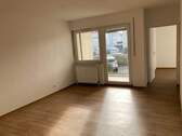 Wohnzimmer mit PVC-Bodenbelag in Holzoptik und Blick zum Balkon und ins Schlafzimmer - 1 Zimmer Etagenwohnung in Friedrichsdorf