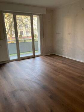 Wohnzimmer mit Zugang zum Balkon. Neuer brauner Vinylboden. Wände tapezierfähig. Decke weiß gestrichen..jpeg - 