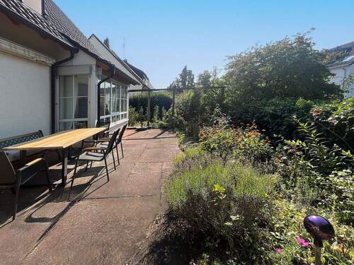 Terrasse am Wohn- und Essbereich, umgeben vom Garten und Blumenbeeten - 