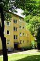 Hausansicht eines mehrstöckigen Wohngebäudes umgeben von Büschen und Bäumen. - 1 Monat mietfrei! 2,5-Zimmer-Wohnung zu vermieten.