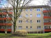 Rückansicht eines mehrstöckigen Wohngebäudes mit Balkonen, umgeben von Bäumen und einer großen grünen Wiese. - 2 Zimmer Etagenwohnung zur Miete in Frankfurt am Main