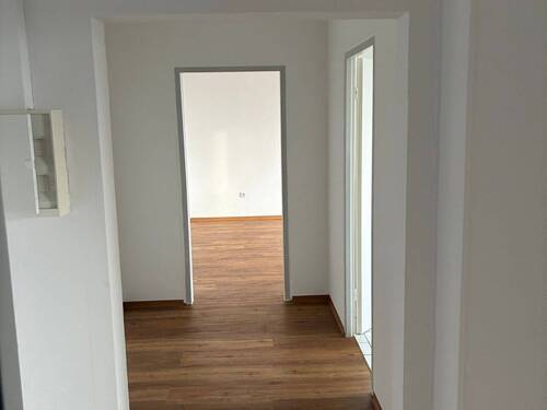 Flur mit Blick Richtung Wohnzimmer, weiß angelegte Wände, brauner Vinyl-Designboden - 