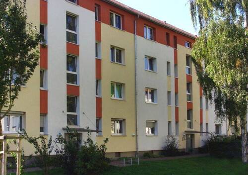 Vorderansicht eines mehrstöckigen Wohngebäudes umgeben von Bäumen und grünen Sträuchern. - 1 Zimmer Etagenwohnung zur Miete in Frankfurt am Main