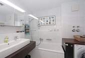 Badezimmer mit Duschwanne, Waschbecken, WC sowie Waschmaschine - 