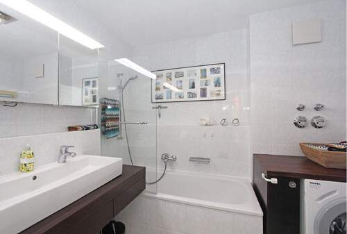 Badezimmer mit Duschwanne, Waschbecken, WC sowie Waschmaschine - 