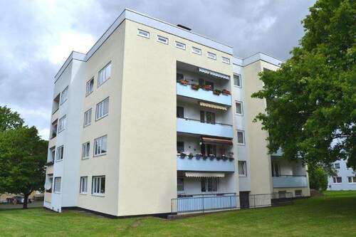 Ansicht des Hausess Friedrich-Ebert-Ring 35 - 4 geschossiges Mehrfamilienhaus mit Flachdach - umgeben von einer grünen Wiese und Bäumen - Familienfreundliche 4-Zimmer-Wohnung zu vermieten