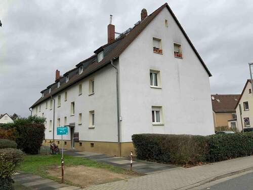 Außenansicht des Mehrfamilienhauses mit heller Fassade und Büschen, sowie Fußweg vor dem Hau - Helle 2,5 Zimmerwohnung mit Loggia