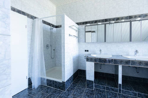 modernes Bad mit großer Dusche und gefliestem Dopp elwaschtisch - 