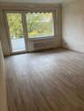Wohnzimmer mit Bodenbelag in Holzoptik und Zugang zum Balkon - 2 Zimmer Etagenwohnung zur Miete in Frankfurt am Main