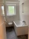 Tageslichtbad mit Badewanne und grauen Bodenfleisen und weißen Wandfliesen - Etagenwohnung mit 56,10 m² in Frankfurt am Main zur Miete