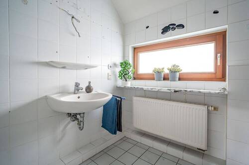 Das Familienbad ist weiß gefliest. - 