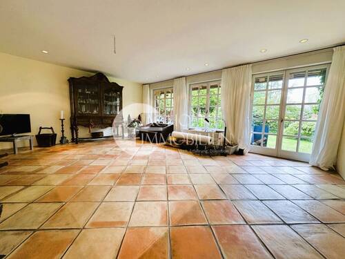 Exklusives Wohnzimmer mit Blick in den Garten und bodentiefen Sprossenfenstern - 