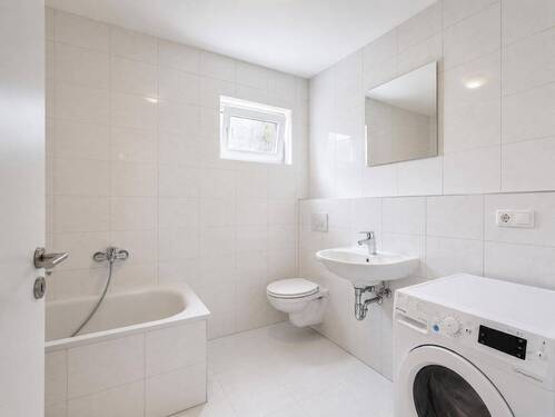 Visualisiert leerstehend: Badezimmer mit Badewanne und hellem Fliesendesign - 