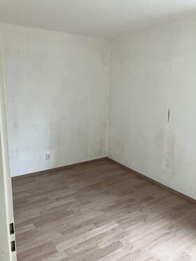 Weiteres Zimmer in weiß gestrichen mit dunkelbraunem Laminatboden beinhaltet ebenfalls ein Fenster - 