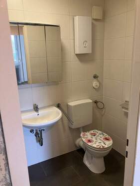 Weißgefliestes Gäste-WC mit schwarzem Fliesenden Boden und einem Wandspiegel - 