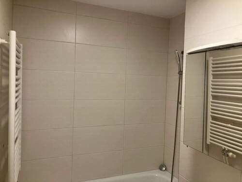 Beige gefliestes Badezimmer mit Badewanne und Wandspiegel - 