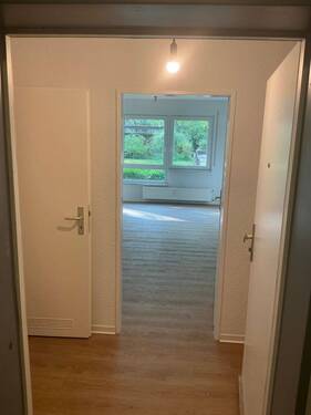 Flur mit neuem Bodenbelag in Holzoptik, Wände tapeziert und weiß angelegt - 